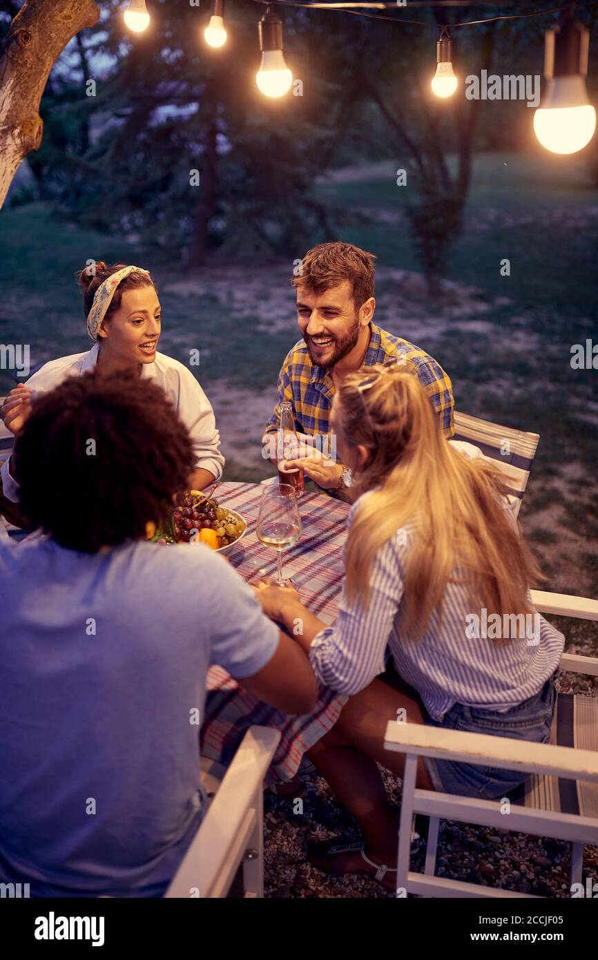 Glückliche Freunde haben eine gute Zeit und lächeln zusammen um einen Tisch. Stockfoto