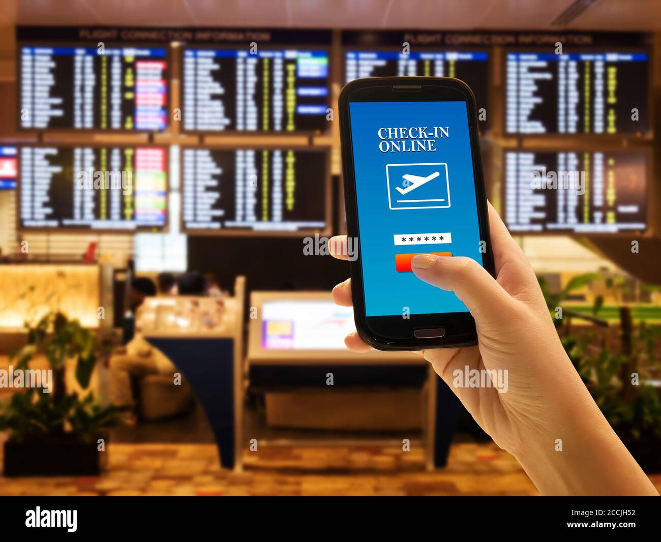 App-Konzept für Reisende-Smartphones. Nahaufnahme der Frau Hand in internationalen Flughafen Verwenden Sie Handy für Online-Check-in mit Fluginformationsbrett BA Stockfoto
