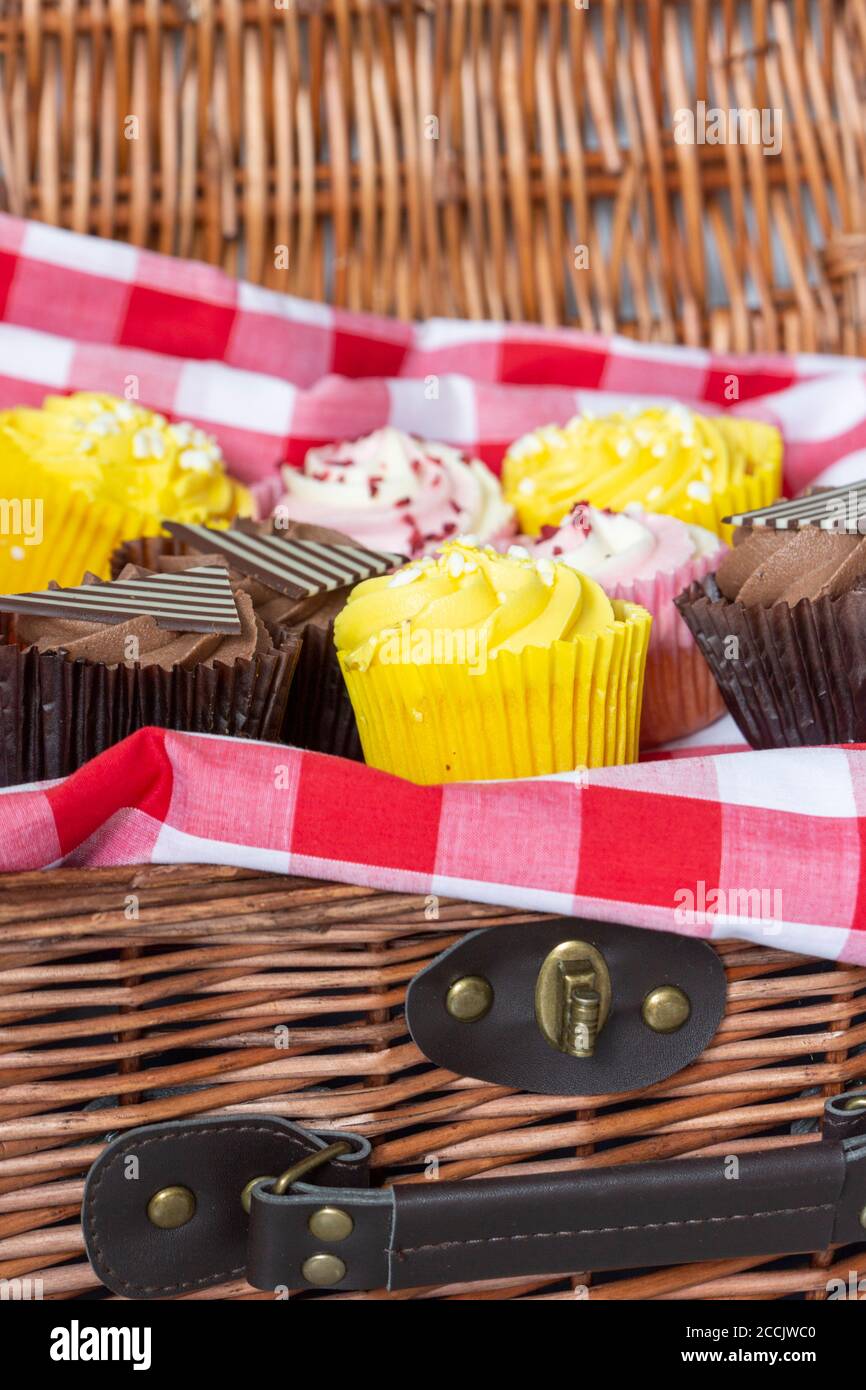Verschiedene Cupcakes in einem Korbpicknickkorb. Mit Gingham-Tuch Stockfoto