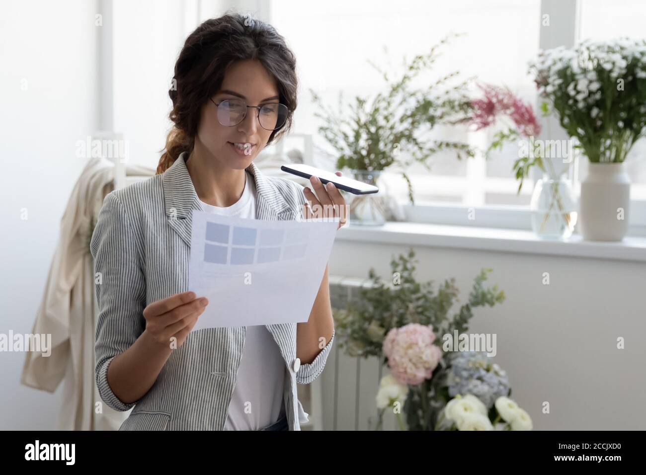Glücklich junge Kleidung Stylistin Aktivierung Stimme Assistent. Stockfoto