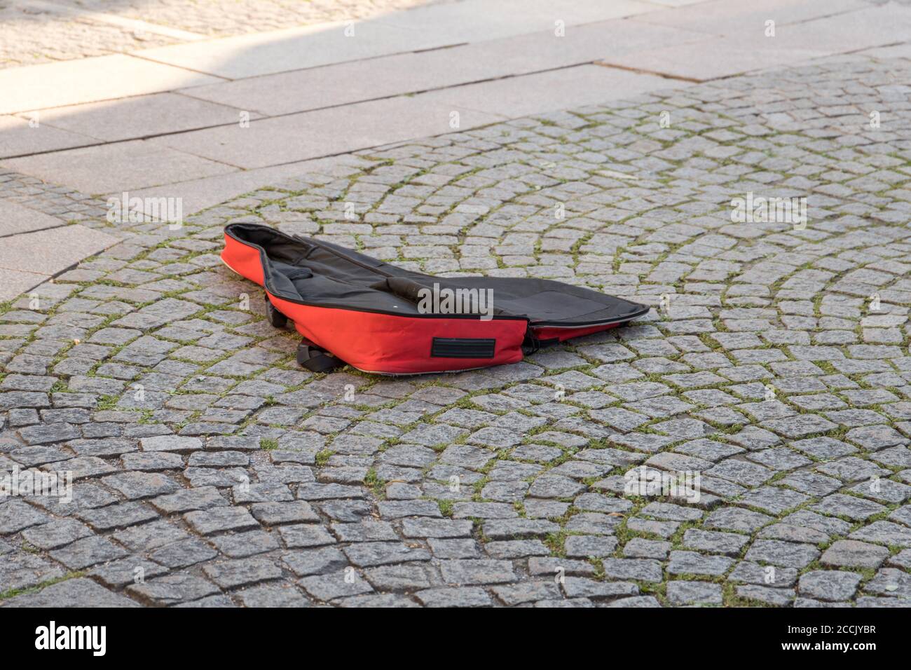 Leeres rotes Gitarrengehäuse eines Straßenmusikers in einem Fußgänger Zone Stockfoto