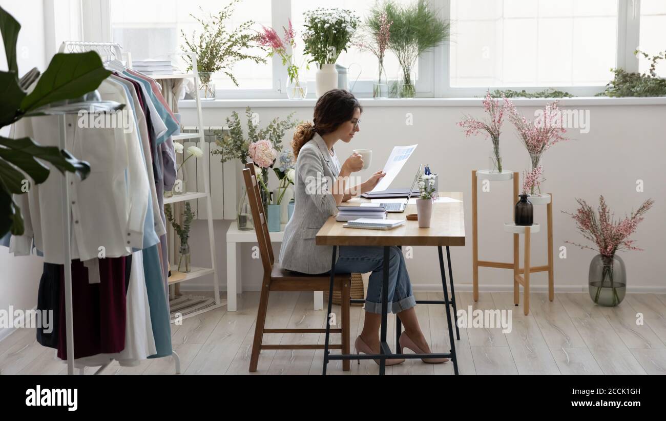 Fokussierte Millennial Mode-Designer Kaffee trinken, arbeiten mit Dokumenten. Stockfoto