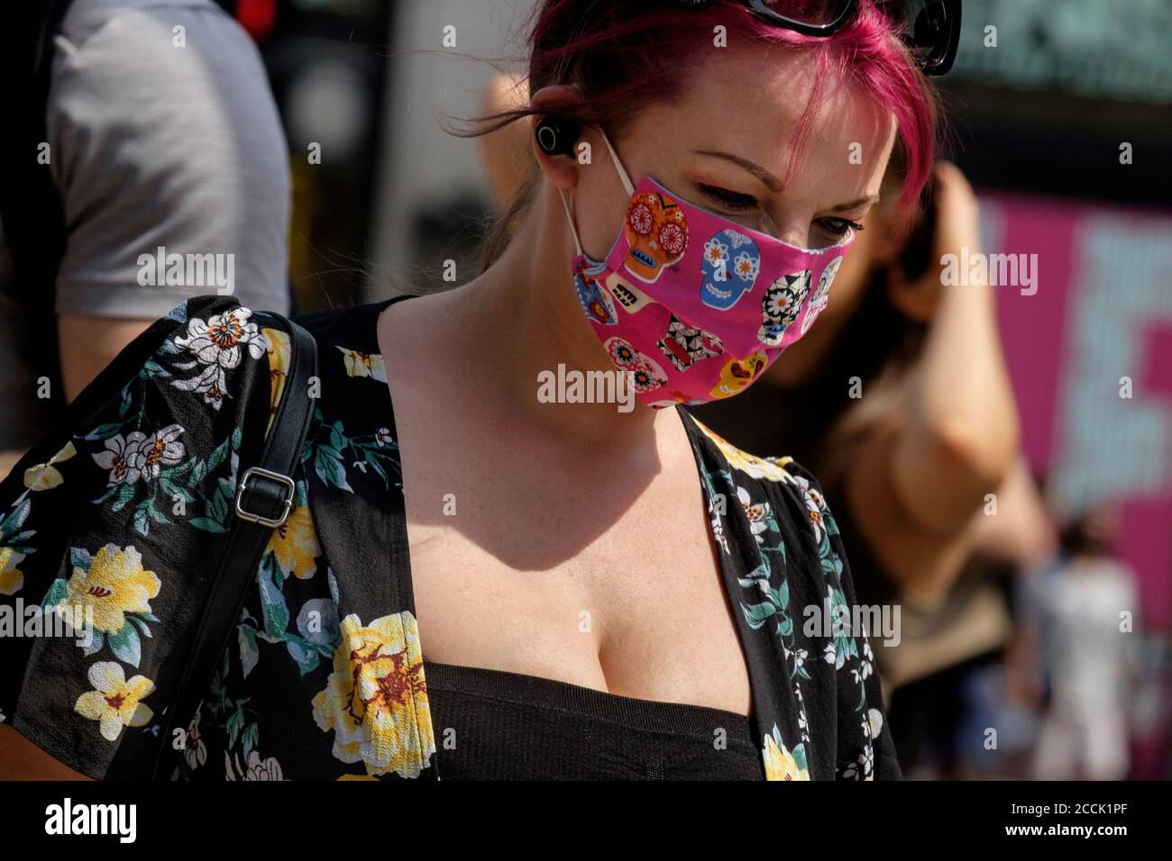 Junge Frau trägt gemusterten Stoff Gesichtsbedeckung in der Straße, London, Großbritannien Stockfoto