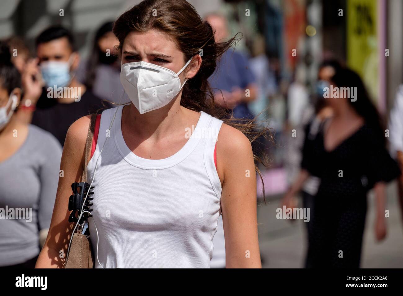Junge Frau mit Gesichtsmaske auf belebten Straße, London, Großbritannien Stockfoto