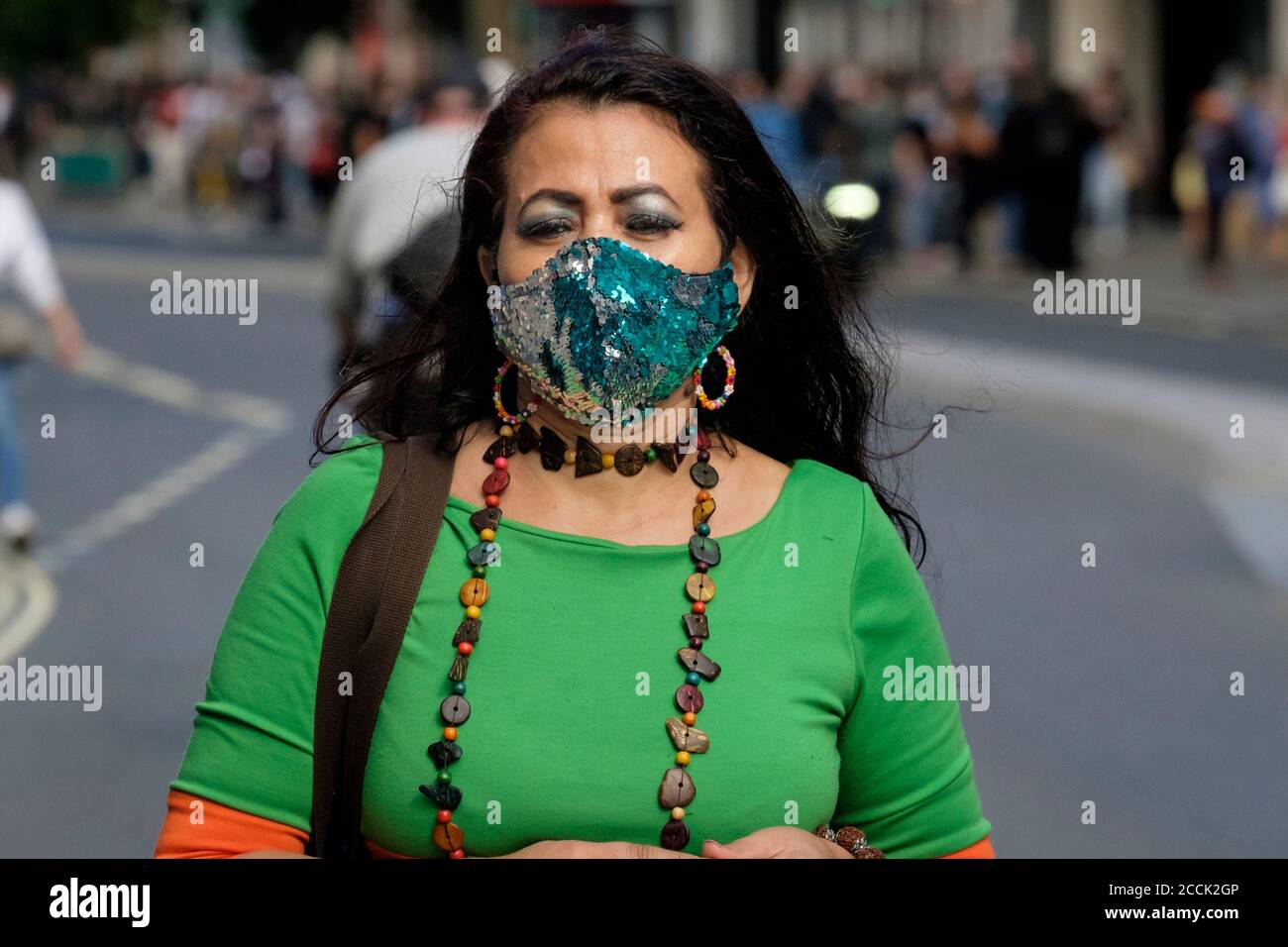 Frauen tragen Pailletten bedeckt Gesichtsmaske in der Straße, London Großbritannien Stockfoto