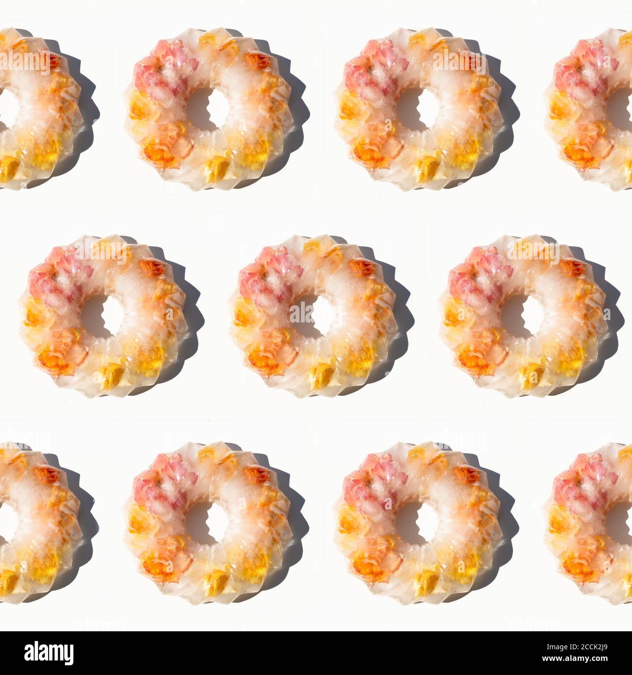 Kreative bunte Obst-Muster von gefrorenen Rosen in Eis auf weißem Hintergrund. Sommerobst Minimales Konzept. Stockfoto