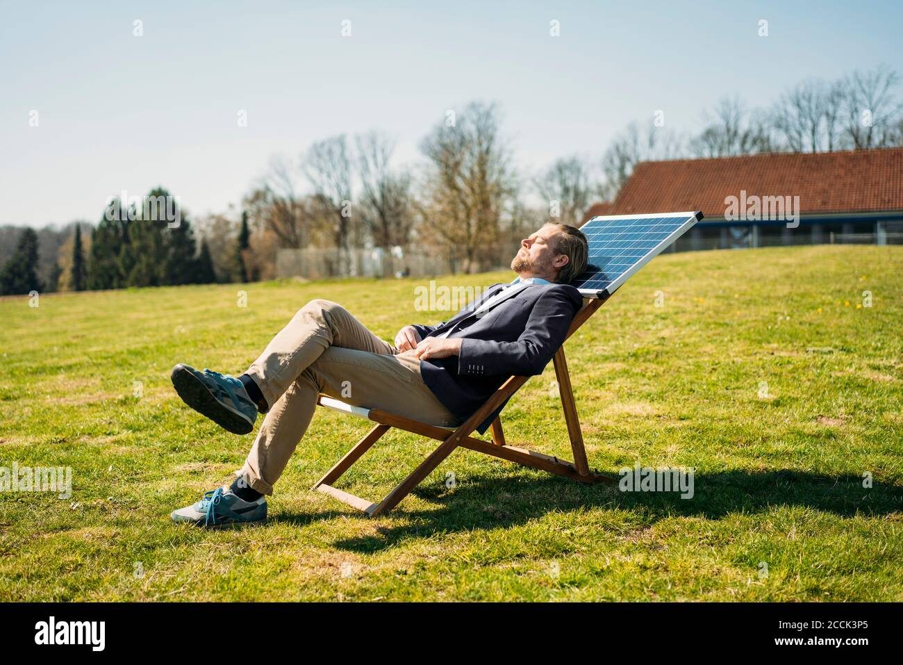 Geschäftsmann entspannen auf Stuhl mit Solarpanel im Park während Sonniger Tag Stockfoto