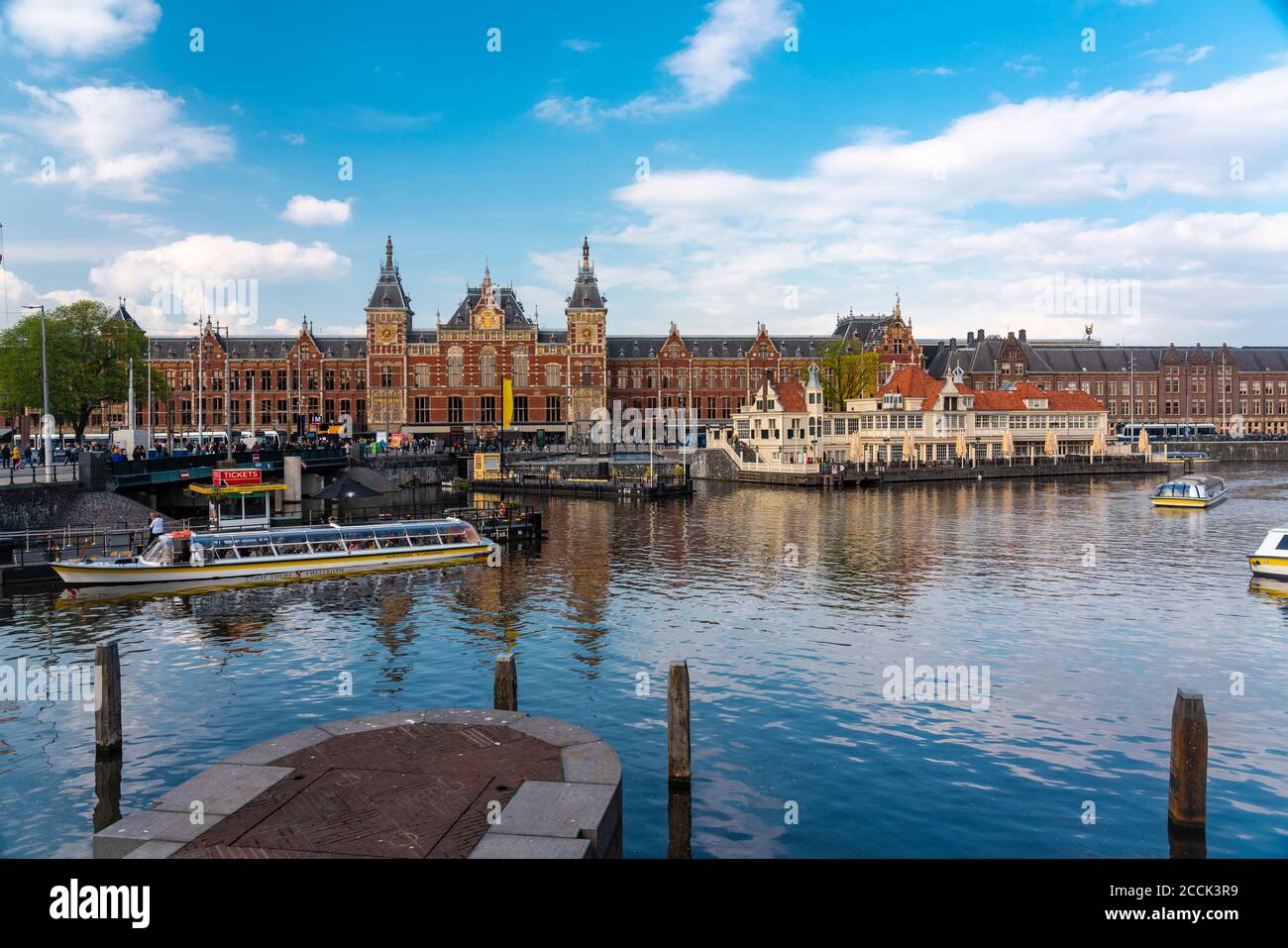 Niederlande, Nordholland, Amsterdam, Stadtkanal mit Amsterdam Centraal Railroad Station im Hintergrund Stockfoto