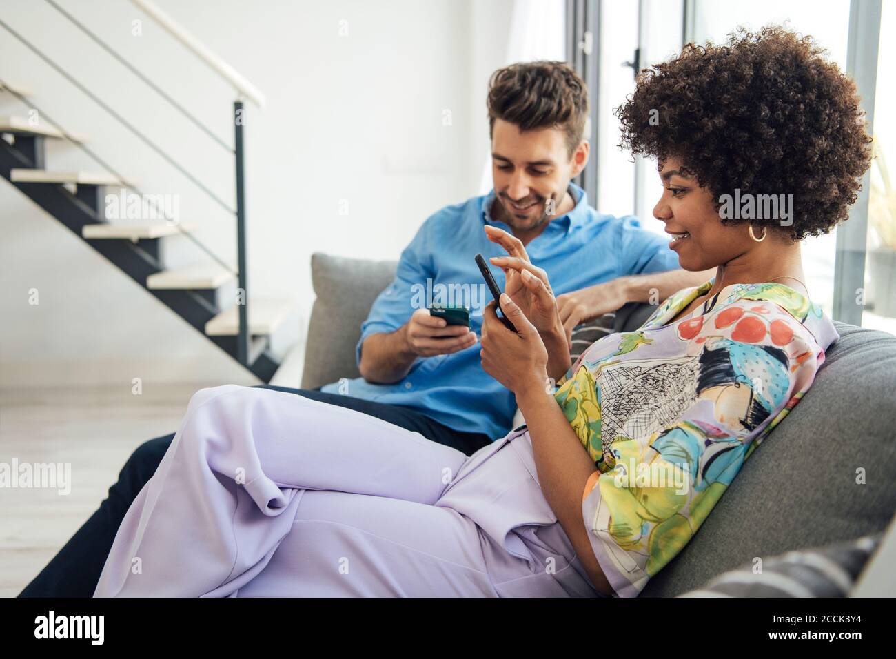 Paar mit Smartphones, während auf dem Sofa in modernen sitzen Penthouse Stockfoto
