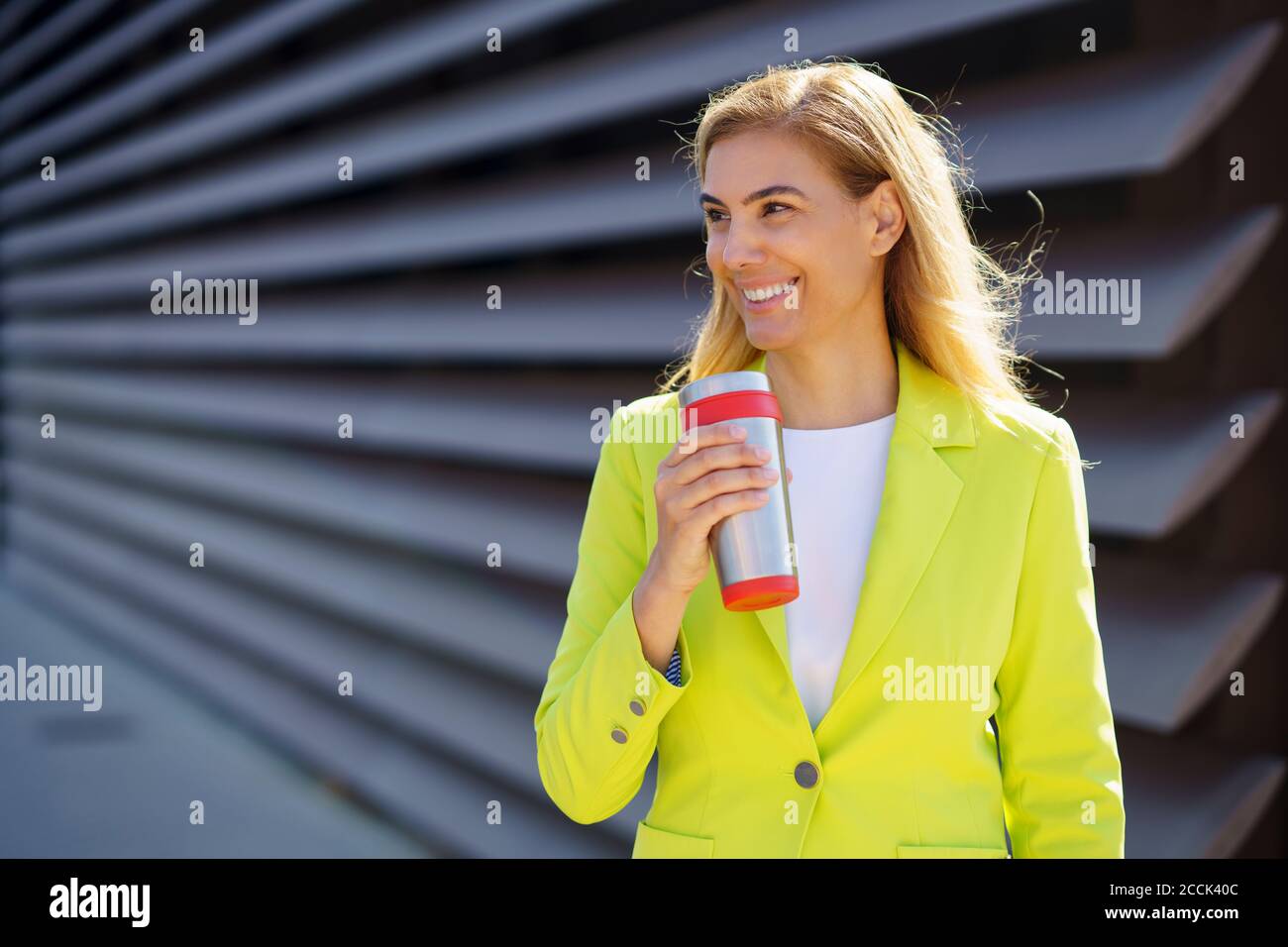Lächelnd reife Geschäftsfrau mit Reise Becher wegschauen Stockfoto