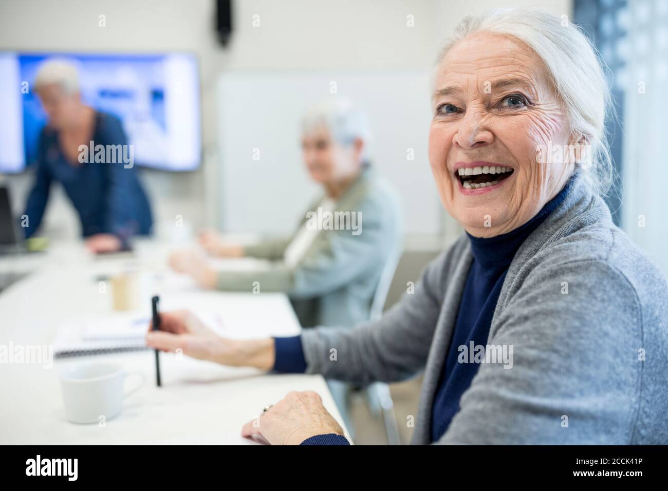 Glückliche ältere Frau, die den Schulkurs für Senioren besucht Stockfoto