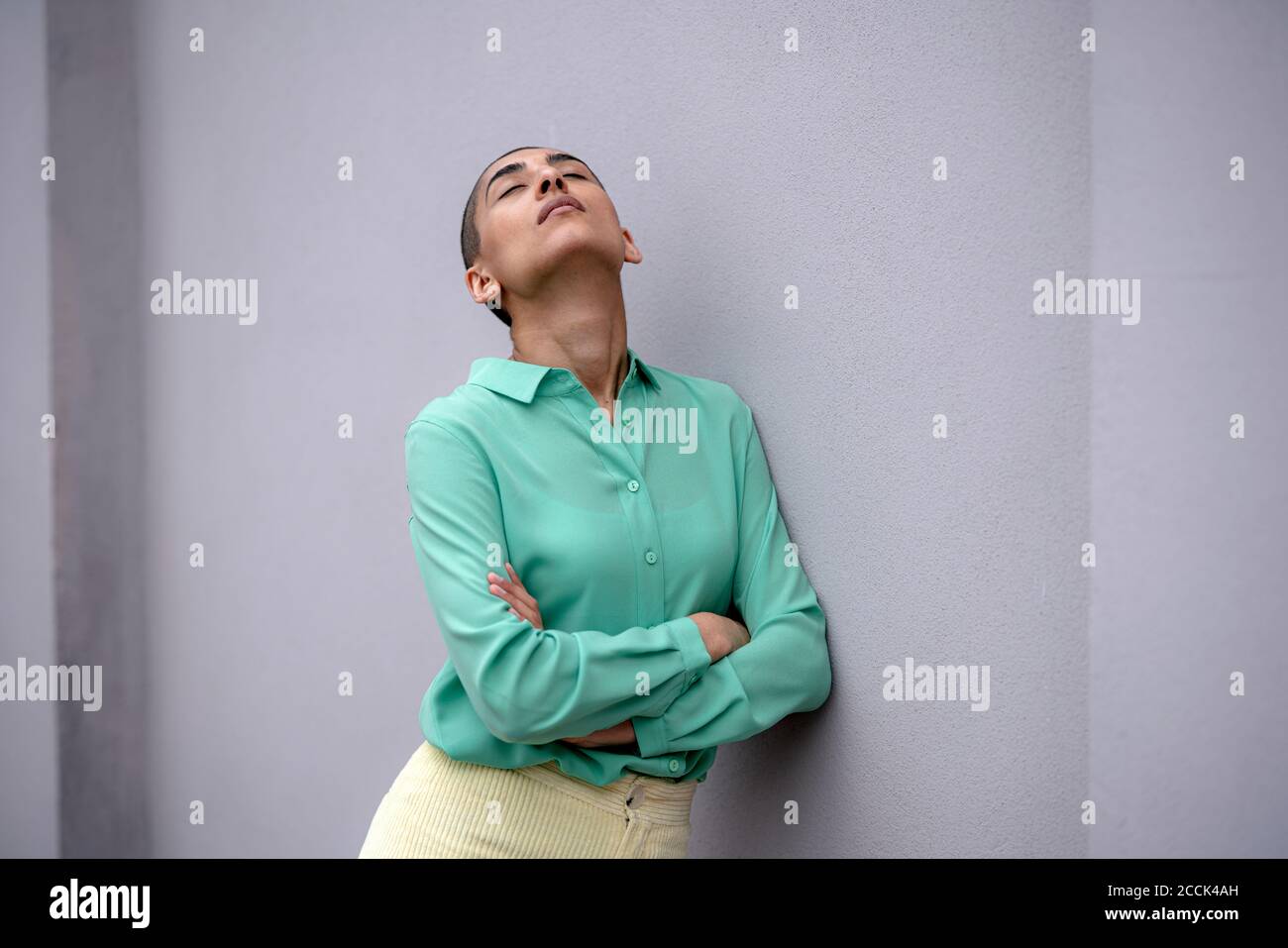 Frau mit geschlossenen Augen an der Wand gelehnt Stockfoto