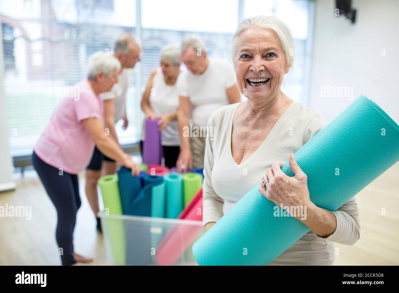 Glückliche ältere Frau mit Yogamatte nach dem Unterricht Stockfoto