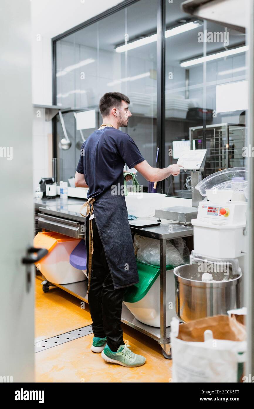 Junger Bäcker, der an der Küchentheke in der Bäckerei arbeitet Stockfoto