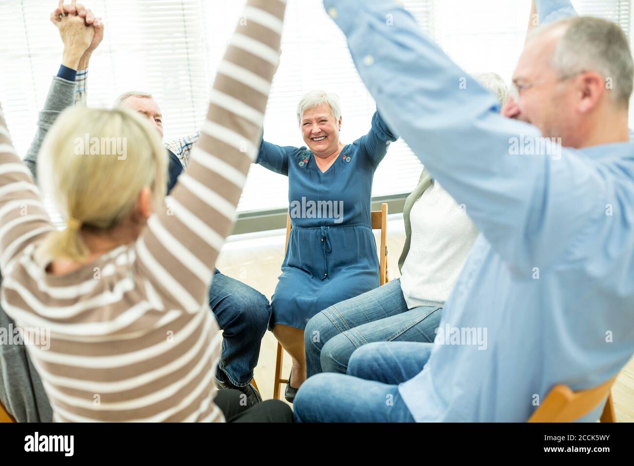 Gruppe von Senioren üben Stuhl Gymnastik mit Lehrer im Ruhestand Zu Hause Stockfoto