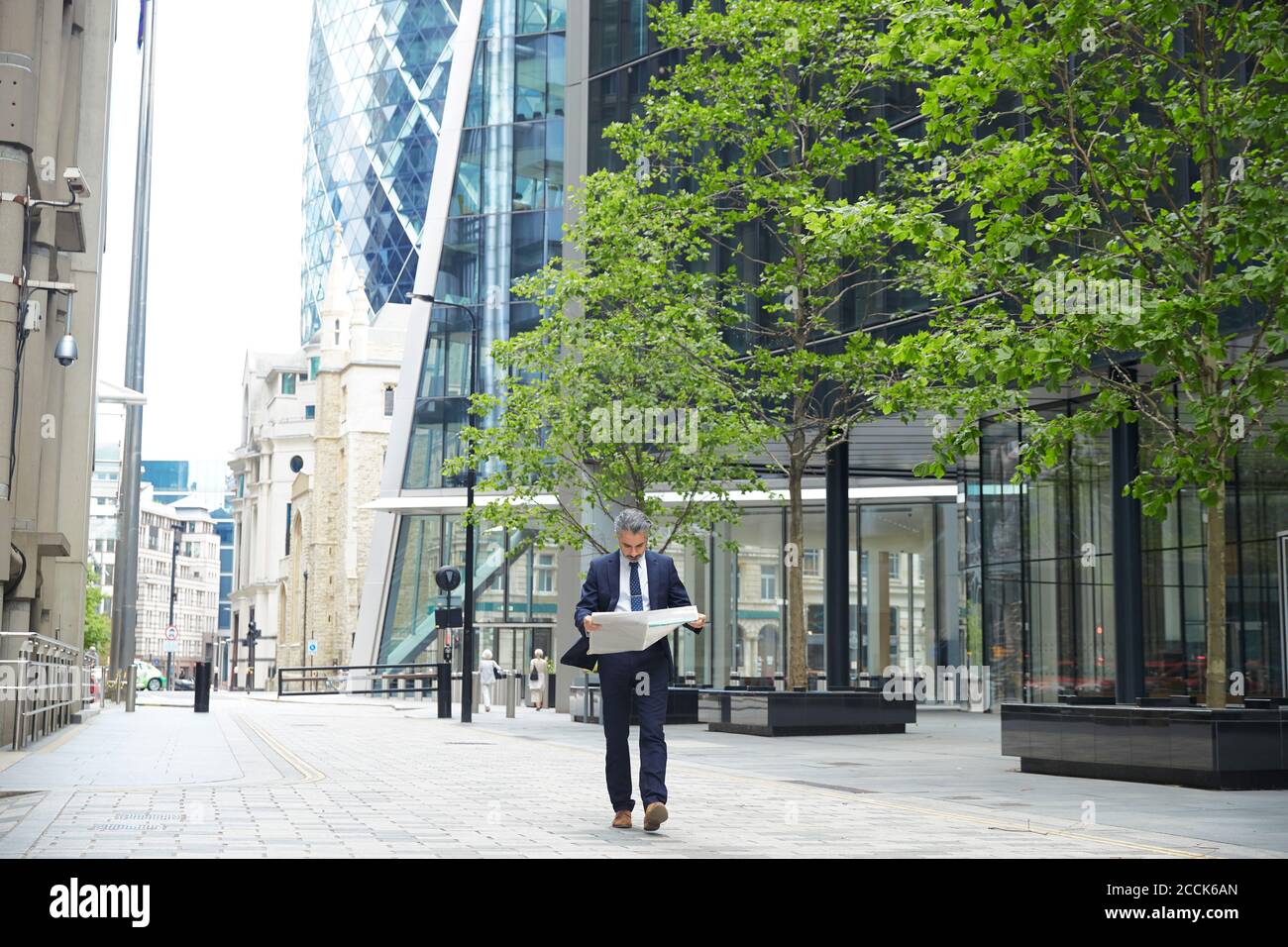Unternehmer Zeitung lesen, während Sie in der Stadt zu Fuß Stockfoto