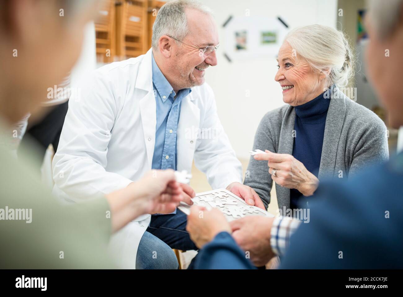 Doktor spielen Puzzle mit Gruppe von Senioren im Ruhestand Zu Hause Stockfoto