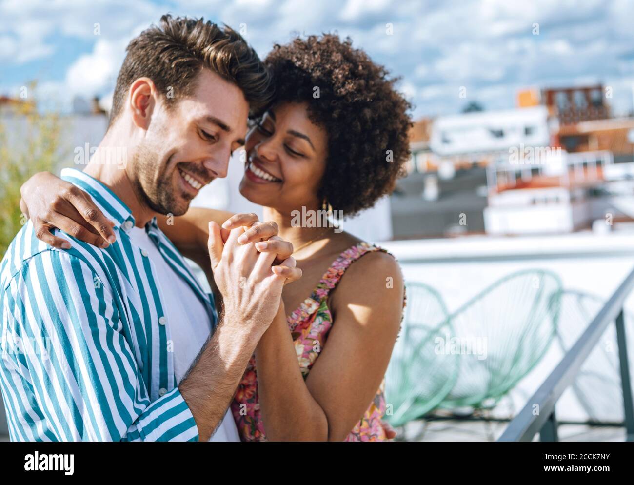 Romantisches multiethnisches Paar, das auf der Penthouse-Terrasse tanzt Stockfoto