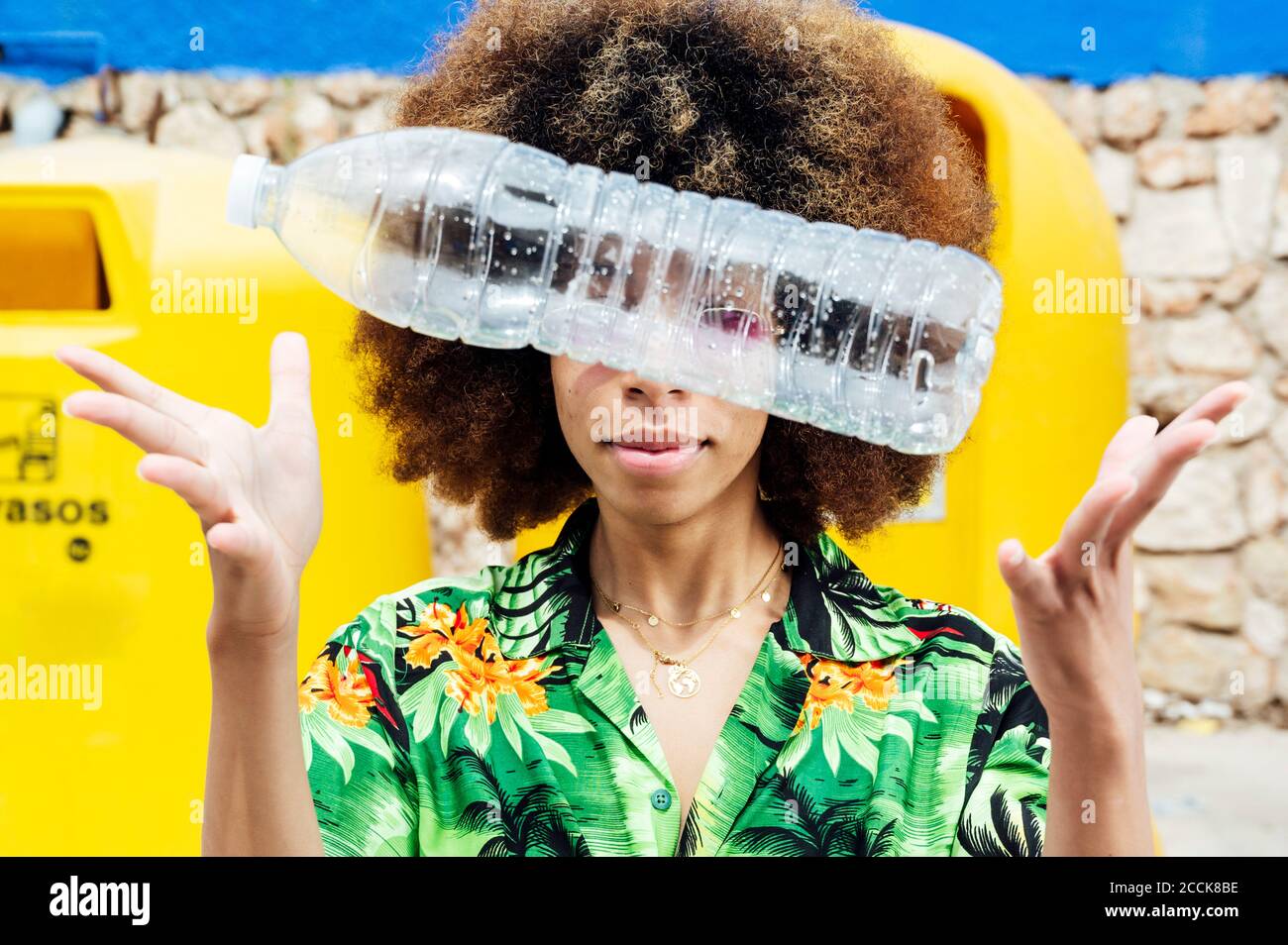 Junge Frau wirft leere Plastikflasche vor dem Recycling Behälter Stockfoto