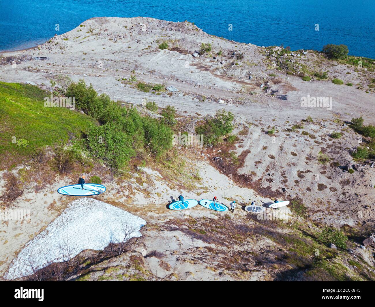 Surfers, die sandigen Hügel in Richtung Ufer des Flusses Teriberka absteigen Stockfoto