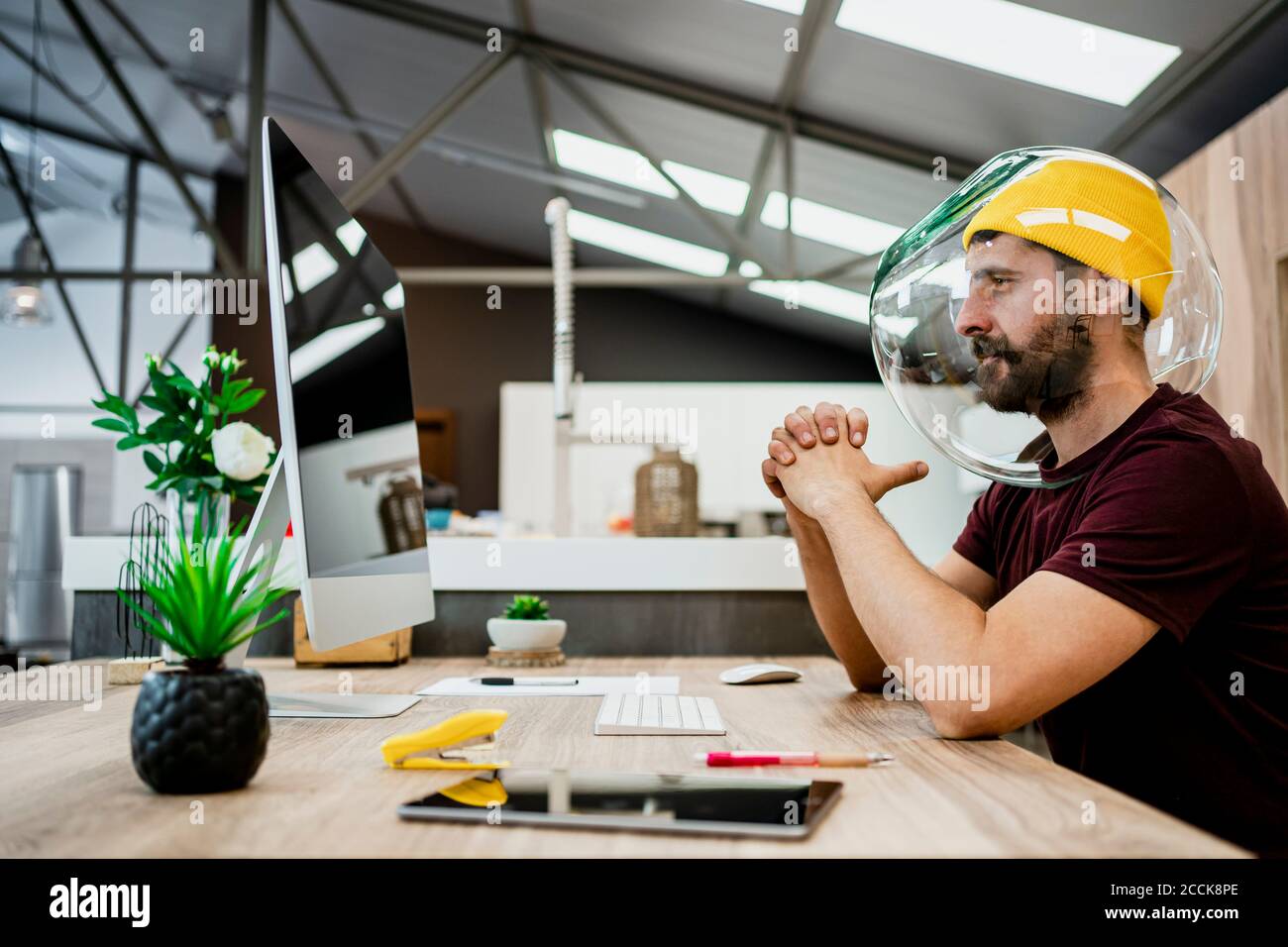 Geschäftsmann trägt Fishbowl während der Verwendung von Computer im modernen Büro Stockfoto