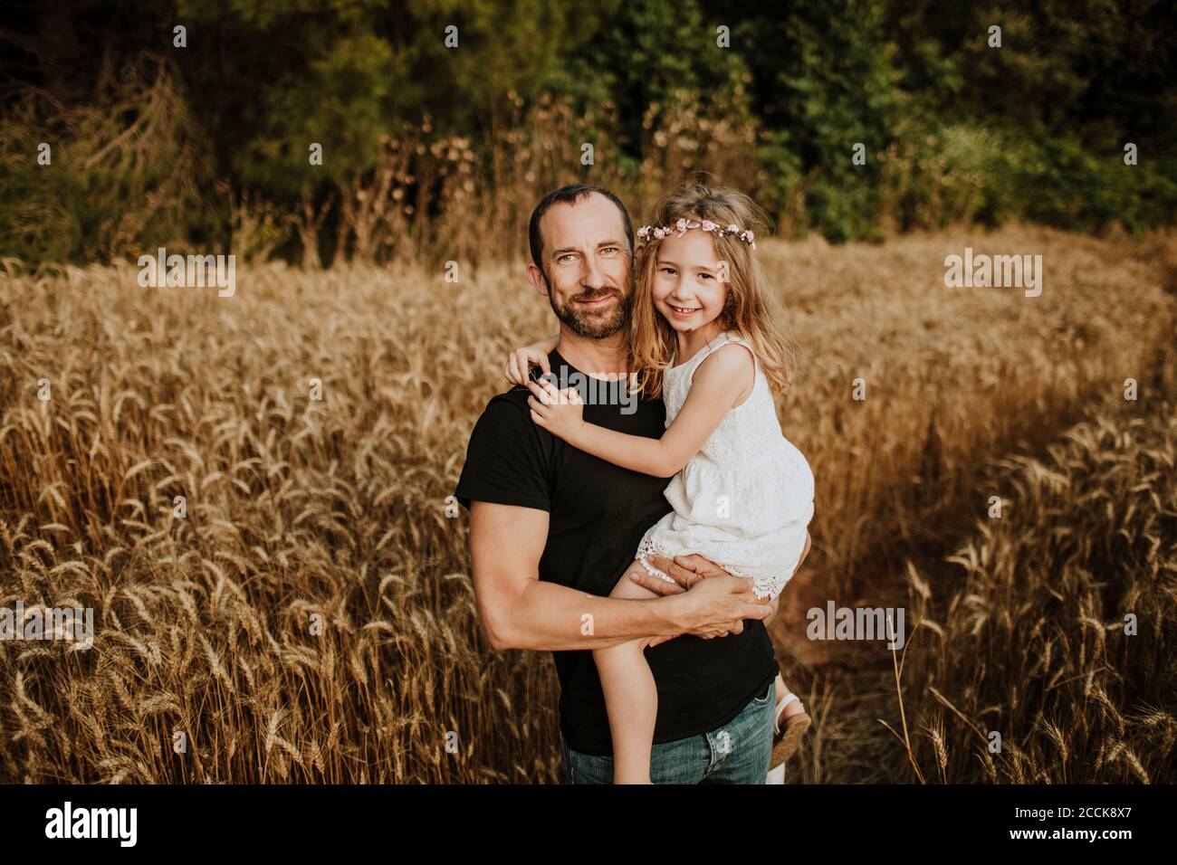 Lächelnder Vater trägt Tochter im Feld des Weizens Stockfoto