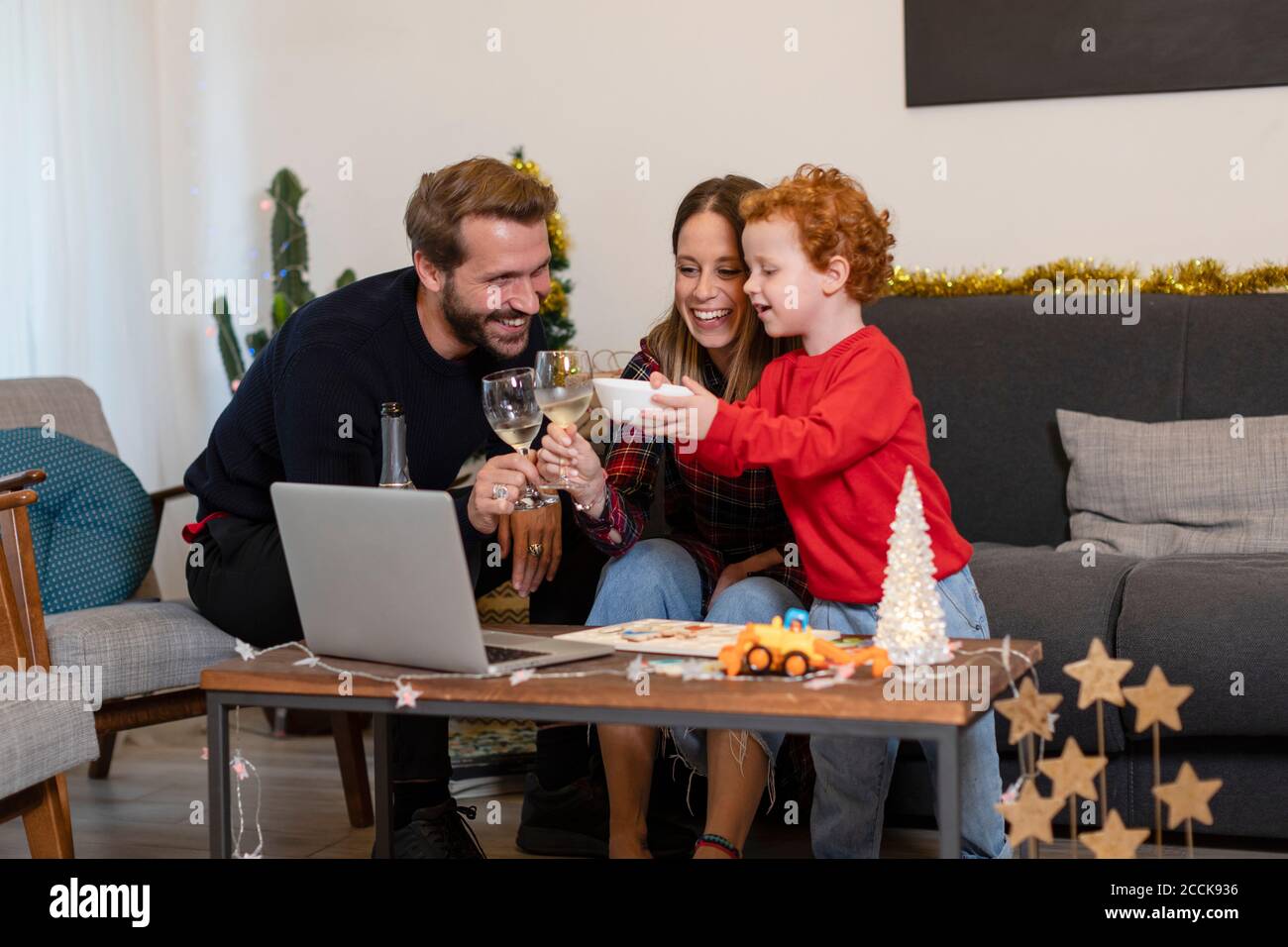 Glückliche Familie toasten Getränke während Videoanrufe über Laptop während Weihnachtsfeier zu Hause Stockfoto