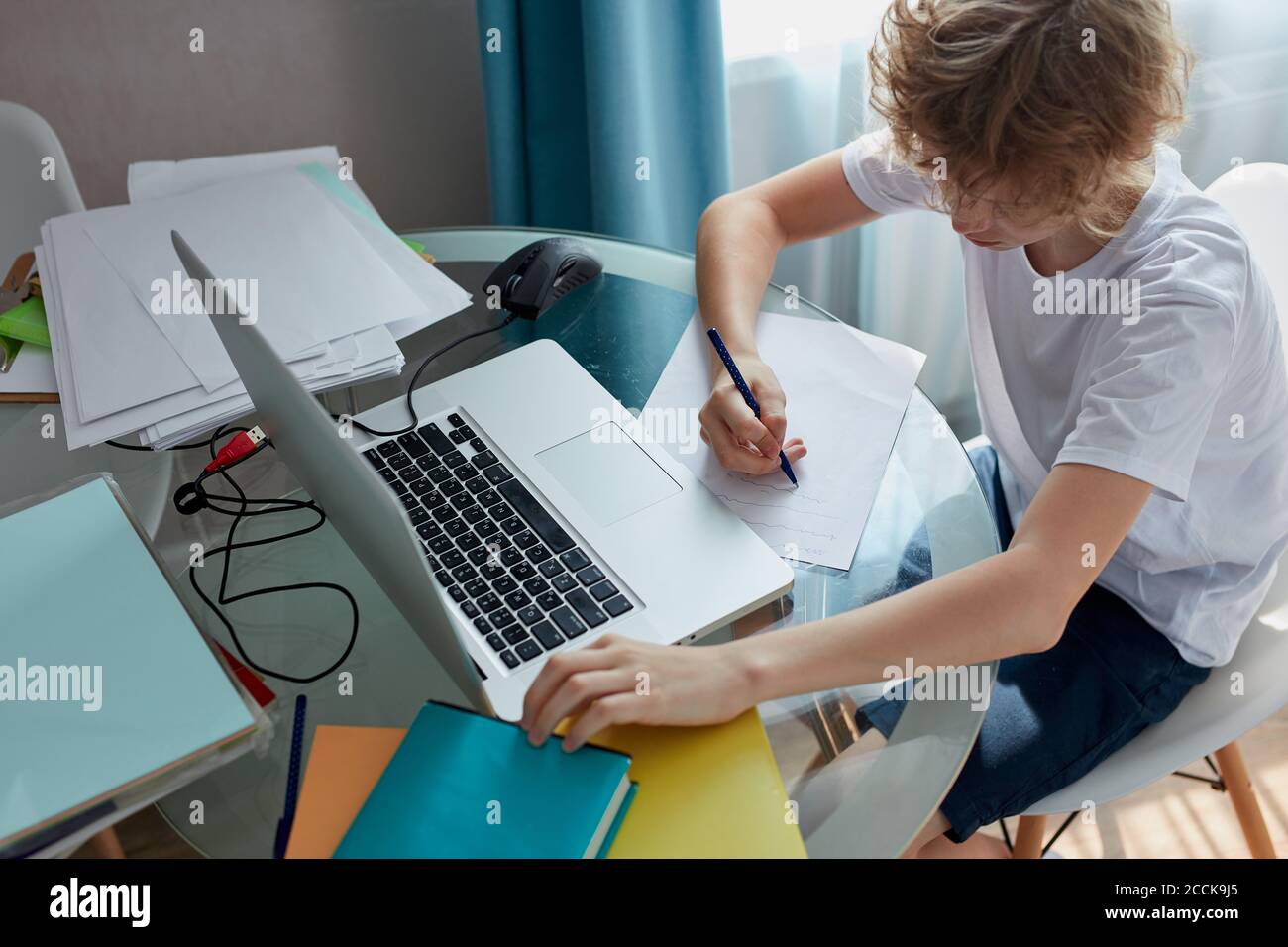 Portrait des jungen kaukasischen Teenager Jungen zu Hause studieren, online studieren, Hausaufgaben während der Quarantäne. Sitzt im Schlafzimmer, trägt Hauskleidung, Aalon Stockfoto
