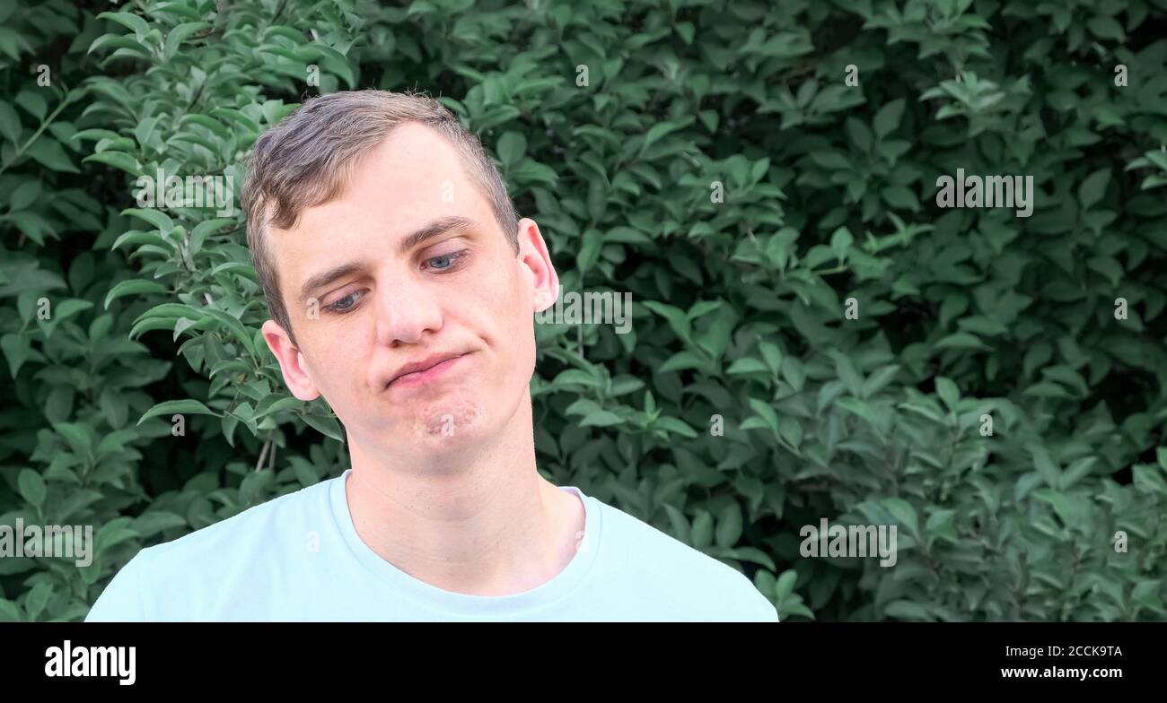 Porträt eines jungen unzufrieden Mann mit blauen Augen auf Ein Hintergrund von Grün Stockfoto