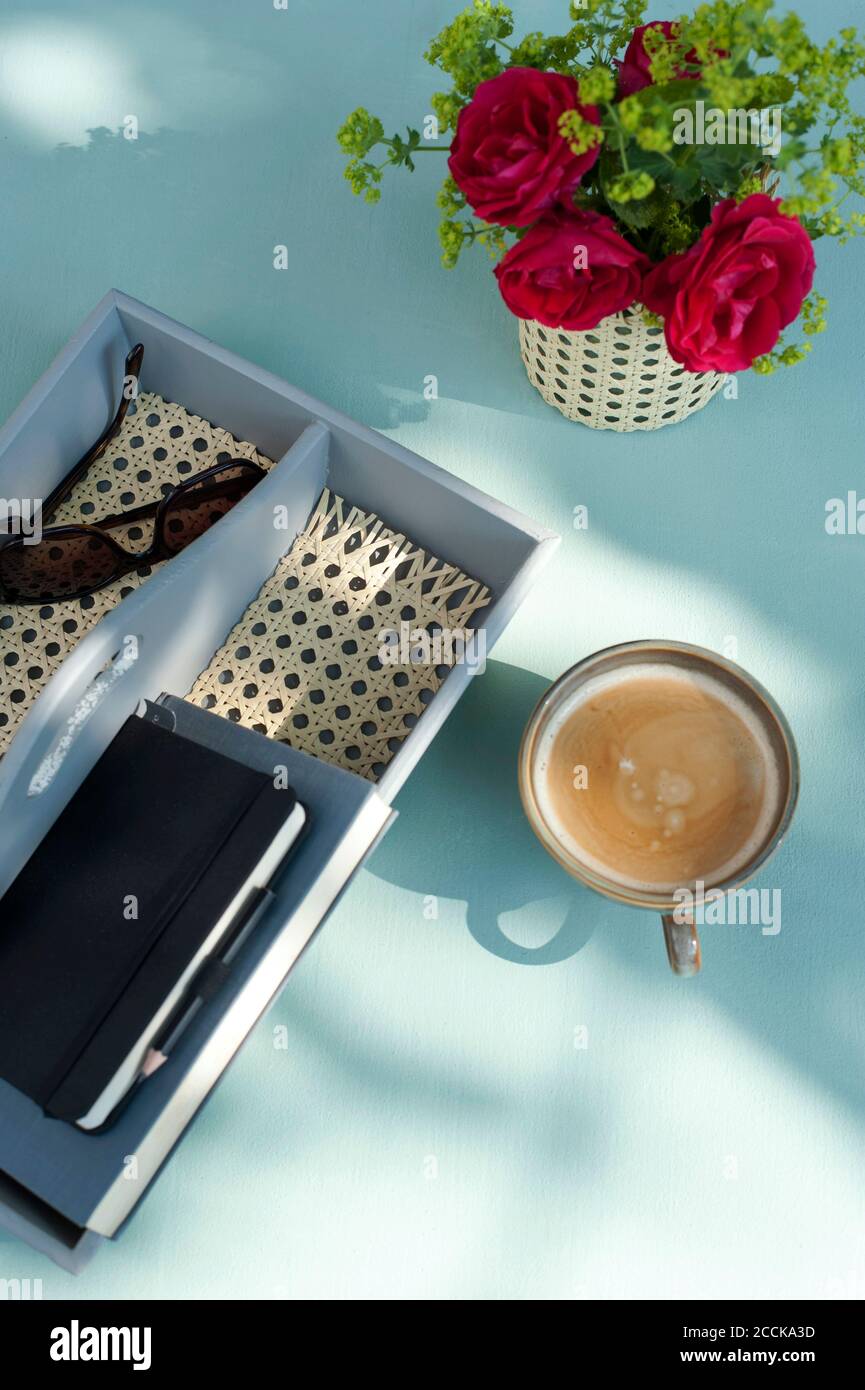 Kaffee, rote Rosen und handgefertigter Tischorganisator mit Sonnenbrille und Notizbuch Stockfoto