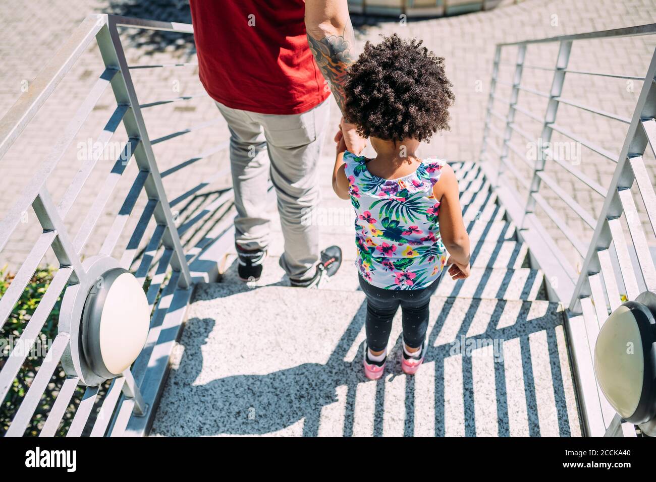 Vater hält die Hände der kleinen Tochter, während er auf Stufen steht Stockfoto