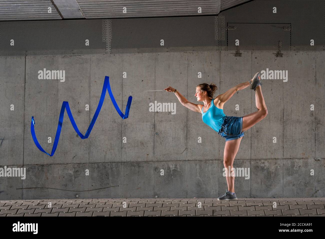Junge Frau Spinnband auf einem Bein gegen Beton stehen Wand unter Brücke Stockfoto