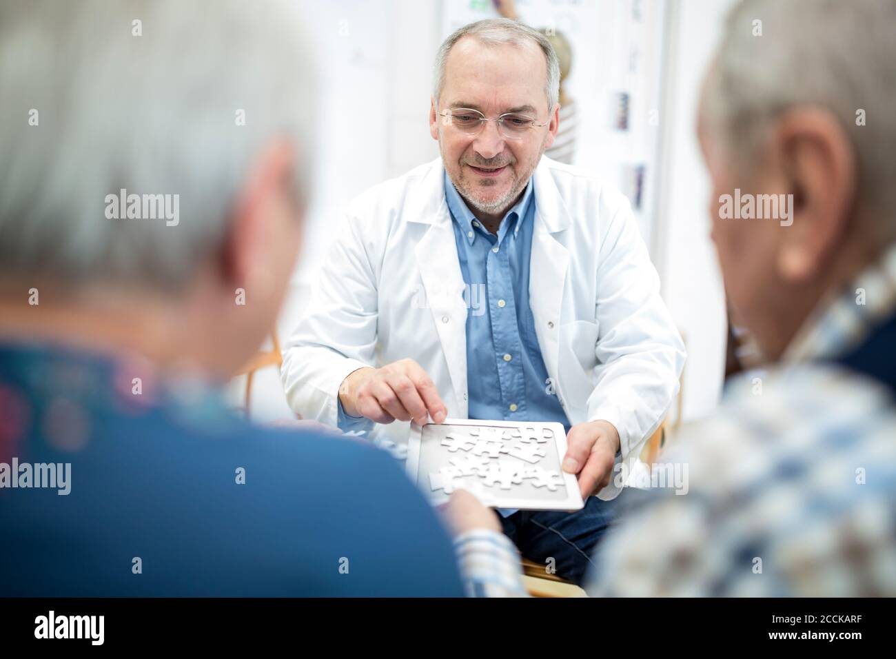 Doktor spielen Puzzle mit Gruppe von Senioren im Ruhestand Zu Hause Stockfoto
