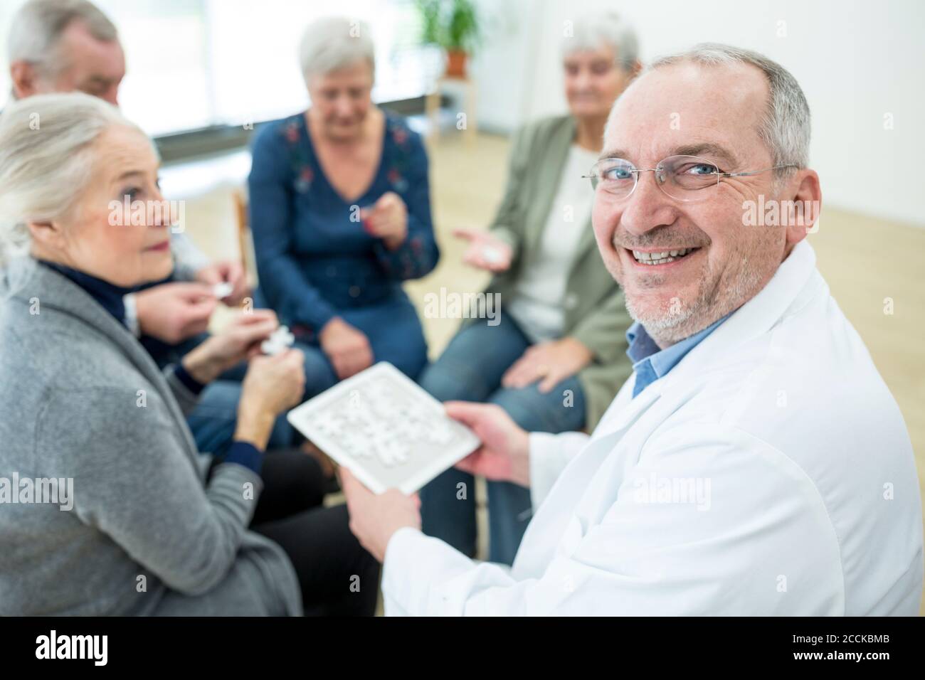 Doktor spielen Puzzle mit Gruppe von Senioren im Ruhestand Zu Hause Stockfoto