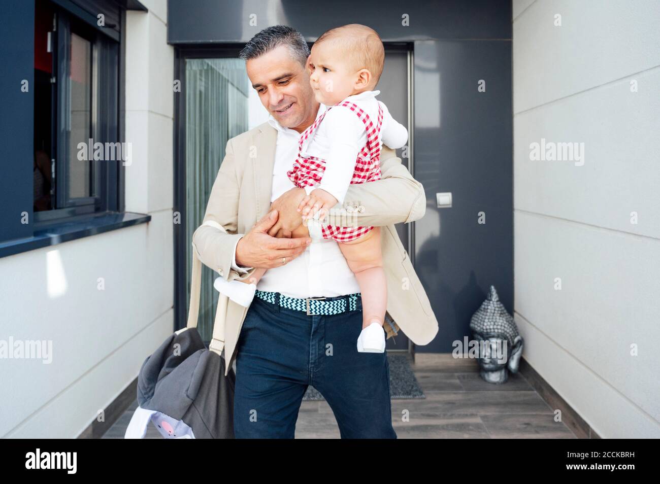 Vater hält seinen kleinen Jungen und verlässt das Haus Stockfoto