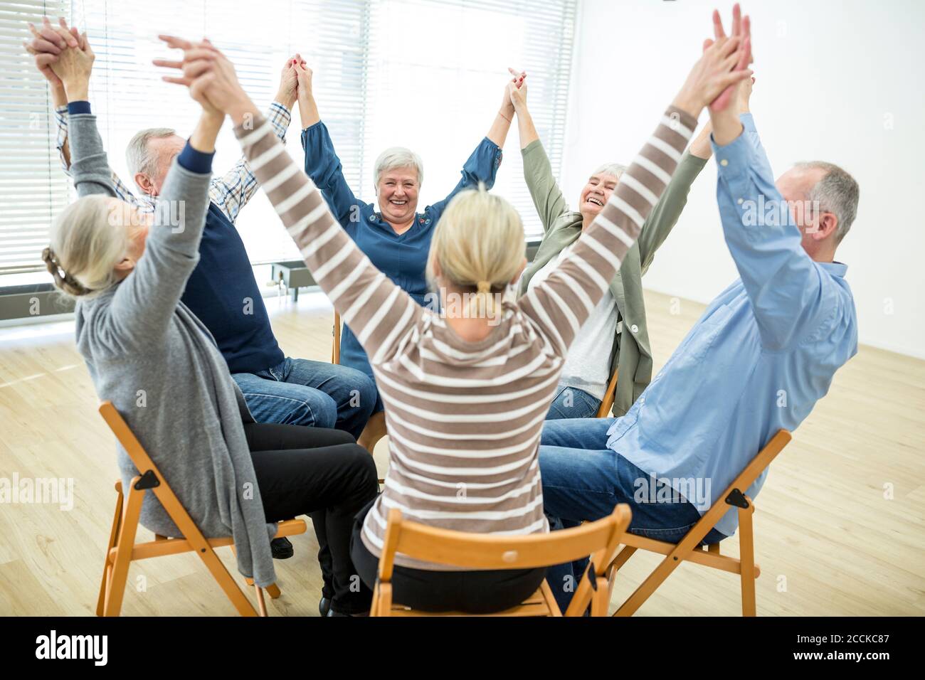 Gruppe von Senioren üben Stuhl Gymnastik mit Lehrer im Ruhestand Zu Hause Stockfoto