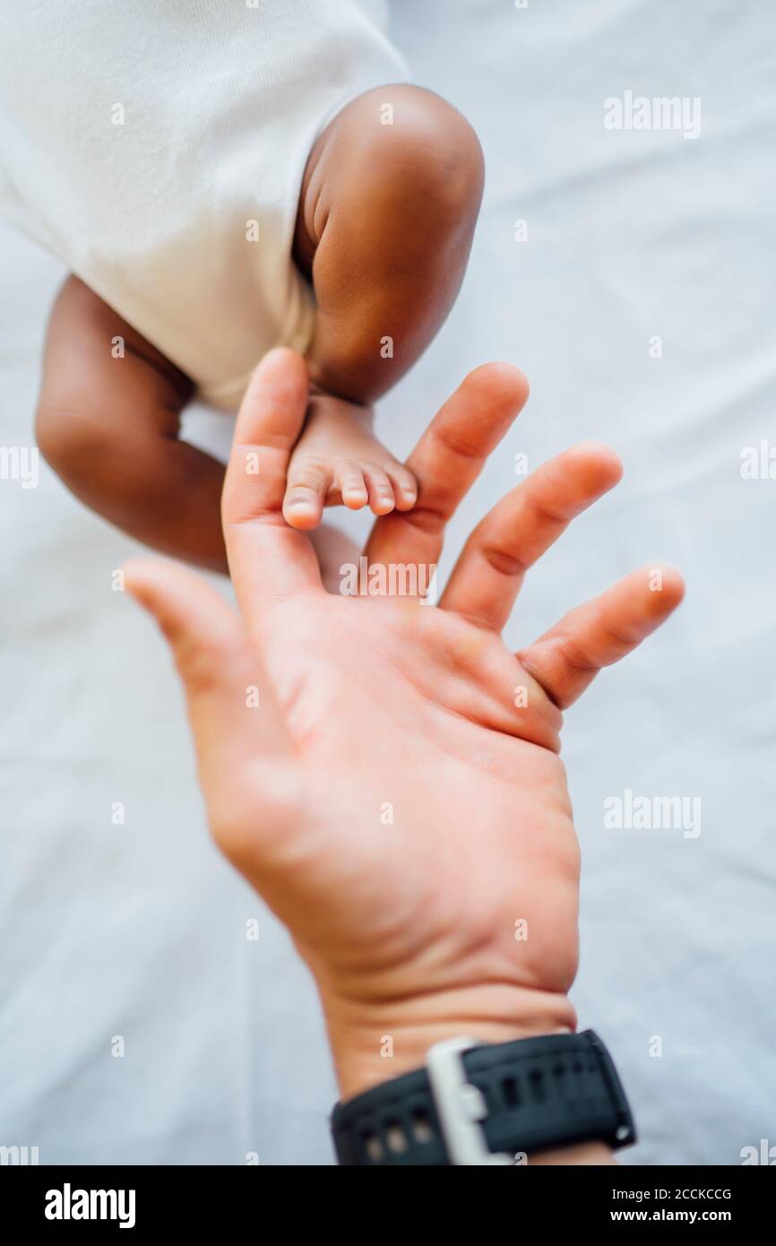 Nahaufnahme der väterlichen Hand, die den Fuß der neugeborenen Tochter auf dem Bett berührt Stockfoto