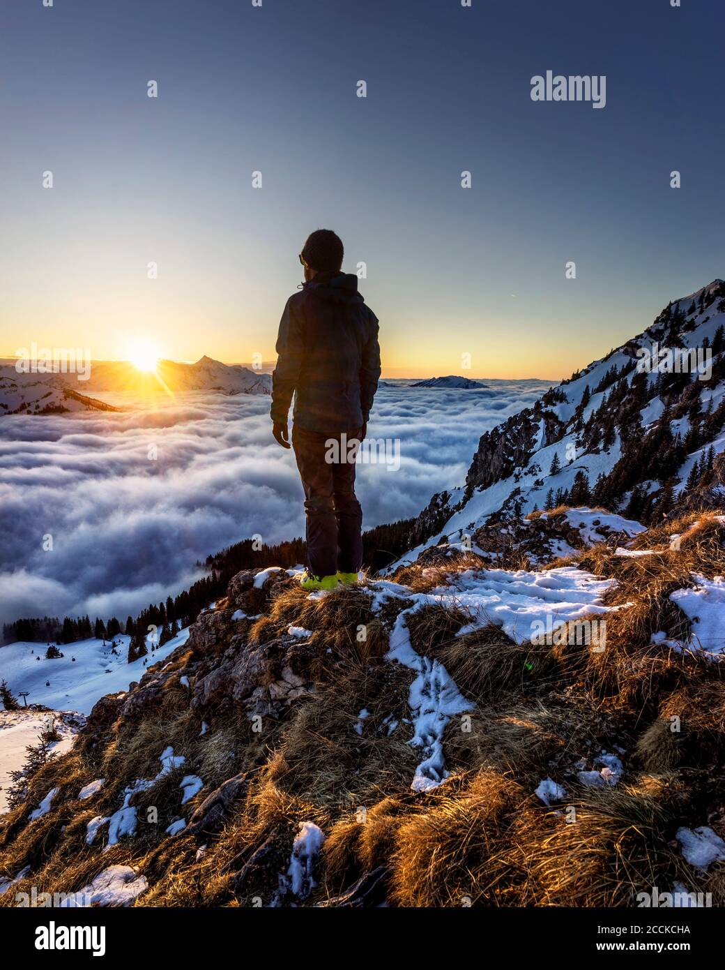 Mann, der den Sonnenaufgang über dem Bergtal bewundert, das in Nebel gehüllt ist Stockfoto
