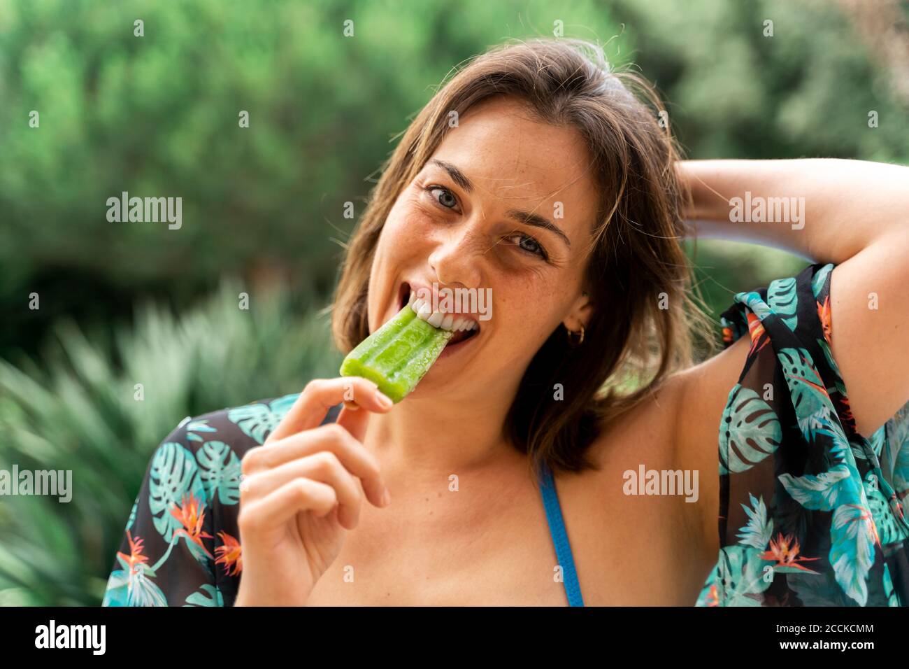 Glückliche junge Frau beim Essen von Eis auf dem Hof Stockfoto