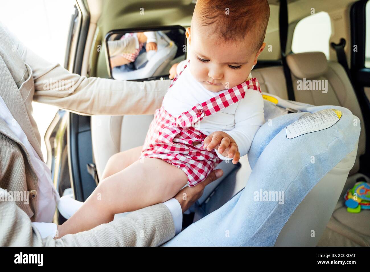 Vater Befestigung Baby Junge sitzen auf Kindersitz in einem Auto Stockfoto