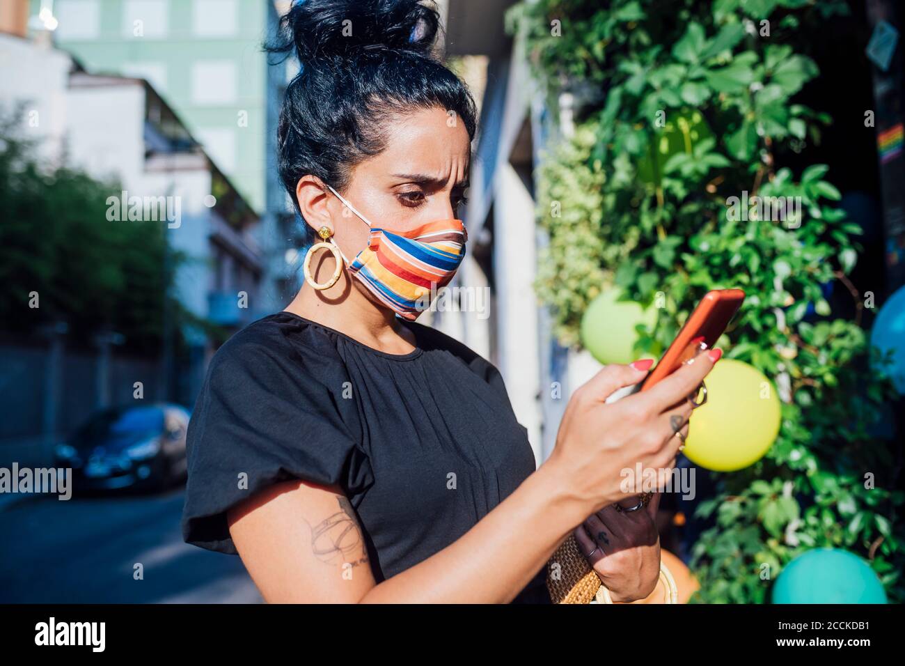 Besorgt Frau mit Telefon, während das Tragen von Maske in der Stadt Stockfoto