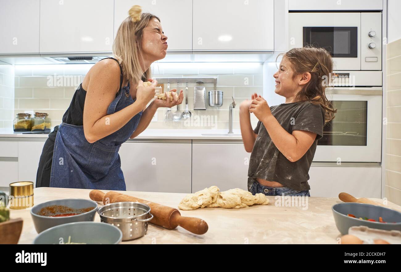Mutter und Tochter spielen mit Pizzateig in der Küche bei Zu Hause Stockfoto