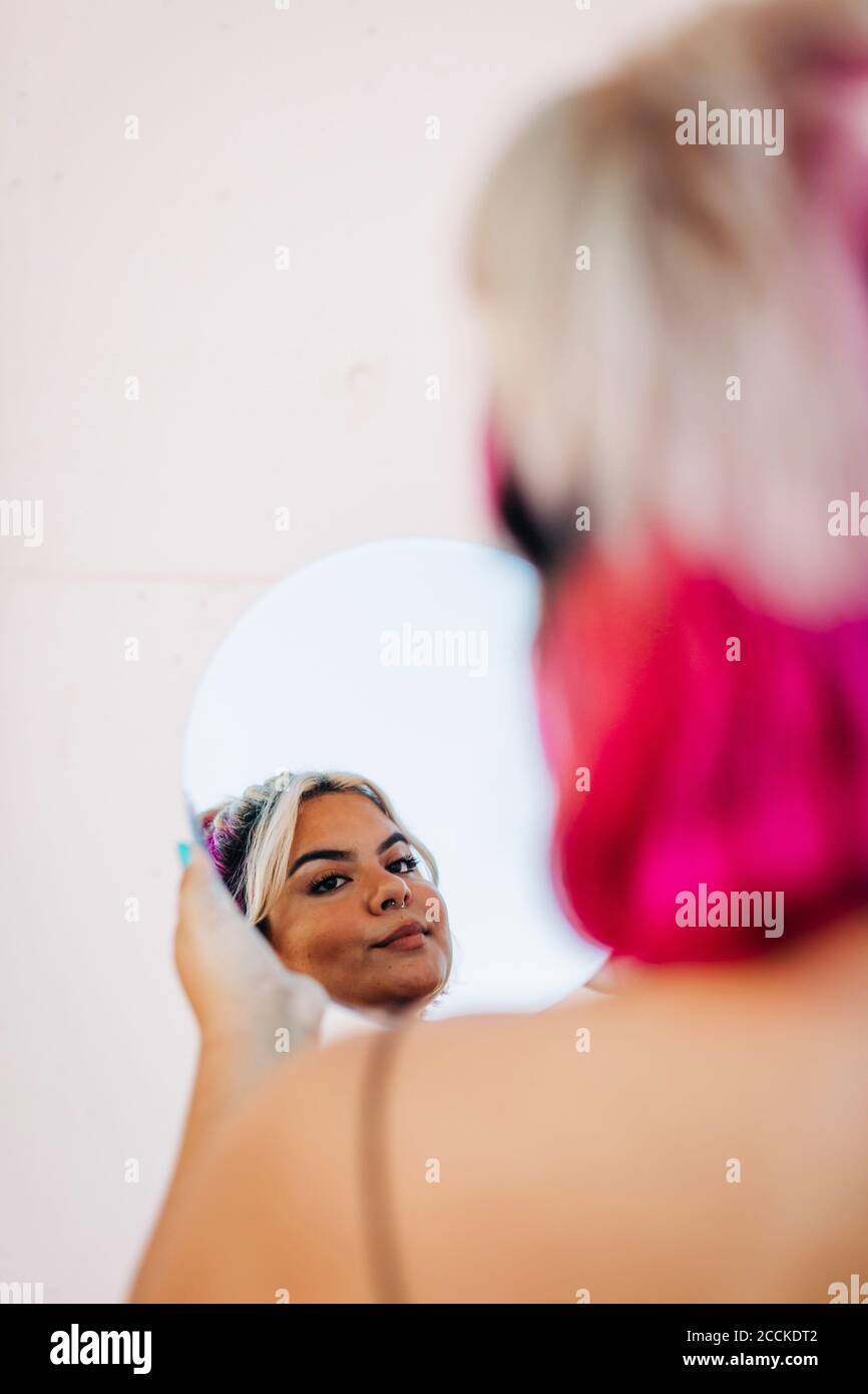 Frau, die ihr Spiegelbild in der Hand Spiegel Stockfoto