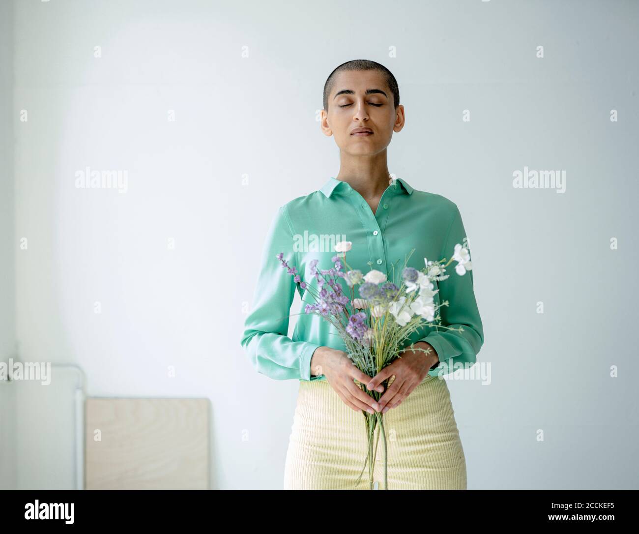 Frau mit geschlossenen Augen hält Blumenstrauß Stockfoto