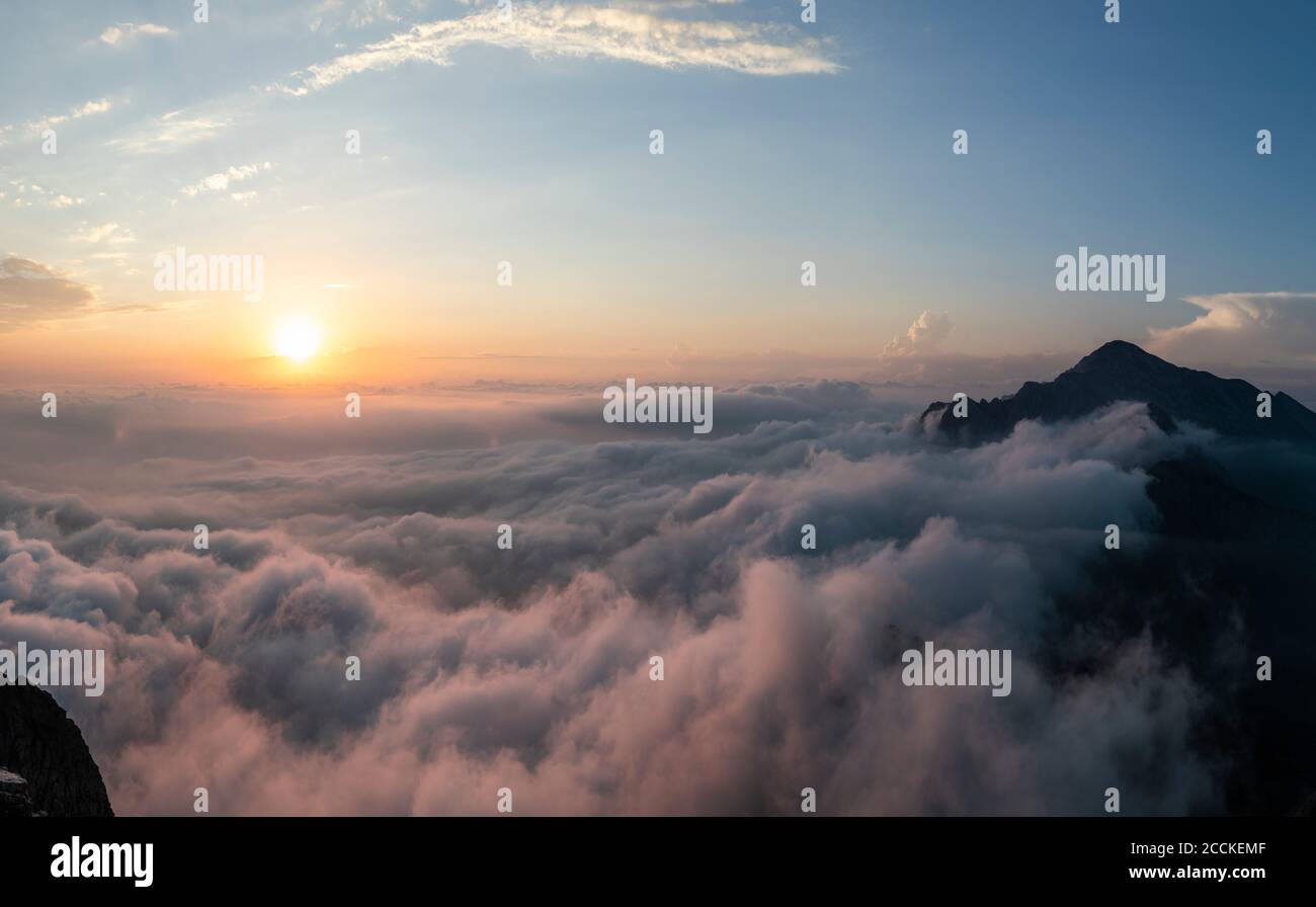 Idyllische Aufnahme von Bergen bedeckt von Wolken während Sonnenaufgang in Bergamasque Alpen, Italien Stockfoto