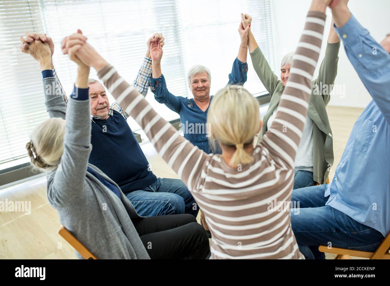 Gruppe von Senioren üben Stuhl Gymnastik mit Lehrer im Ruhestand Zu Hause Stockfoto