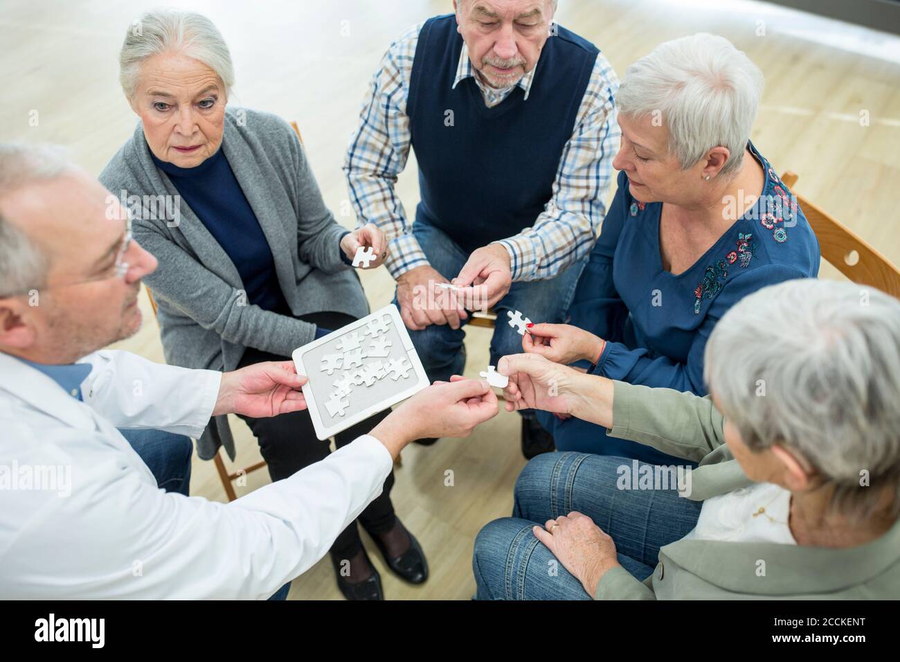 Doktor spielen Puzzle mit Gruppe von Senioren im Ruhestand Zu Hause Stockfoto