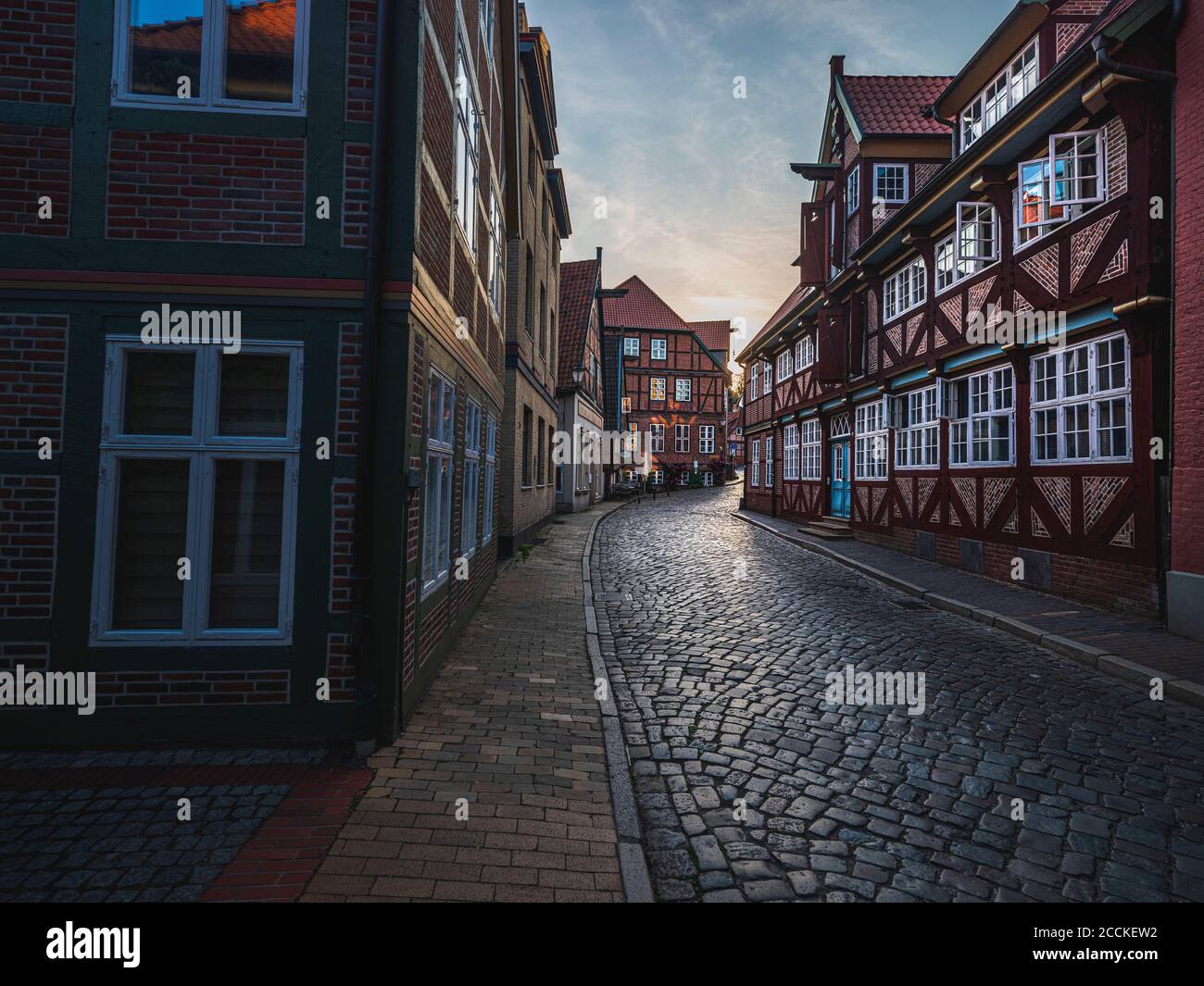 Deutschland, Schleswig-Holstein, Lauenburg, Ziegelhäuser entlang leerer gepflasterter Stadtstraße in der Abenddämmerung Stockfoto