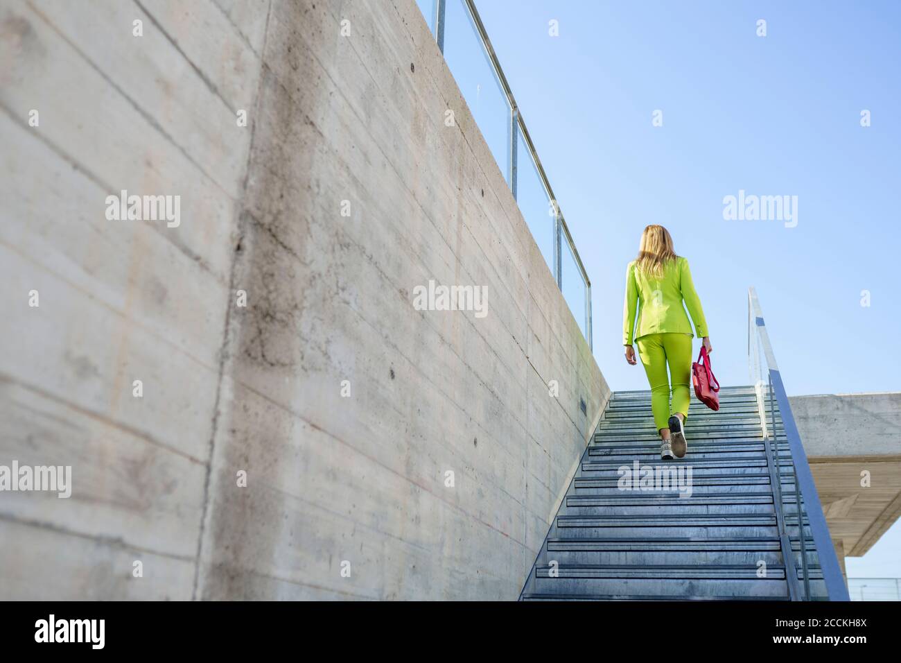 Geschäftsfrau bewegt sich an sonnigen Tagen auf Stufen an Wand Stockfoto