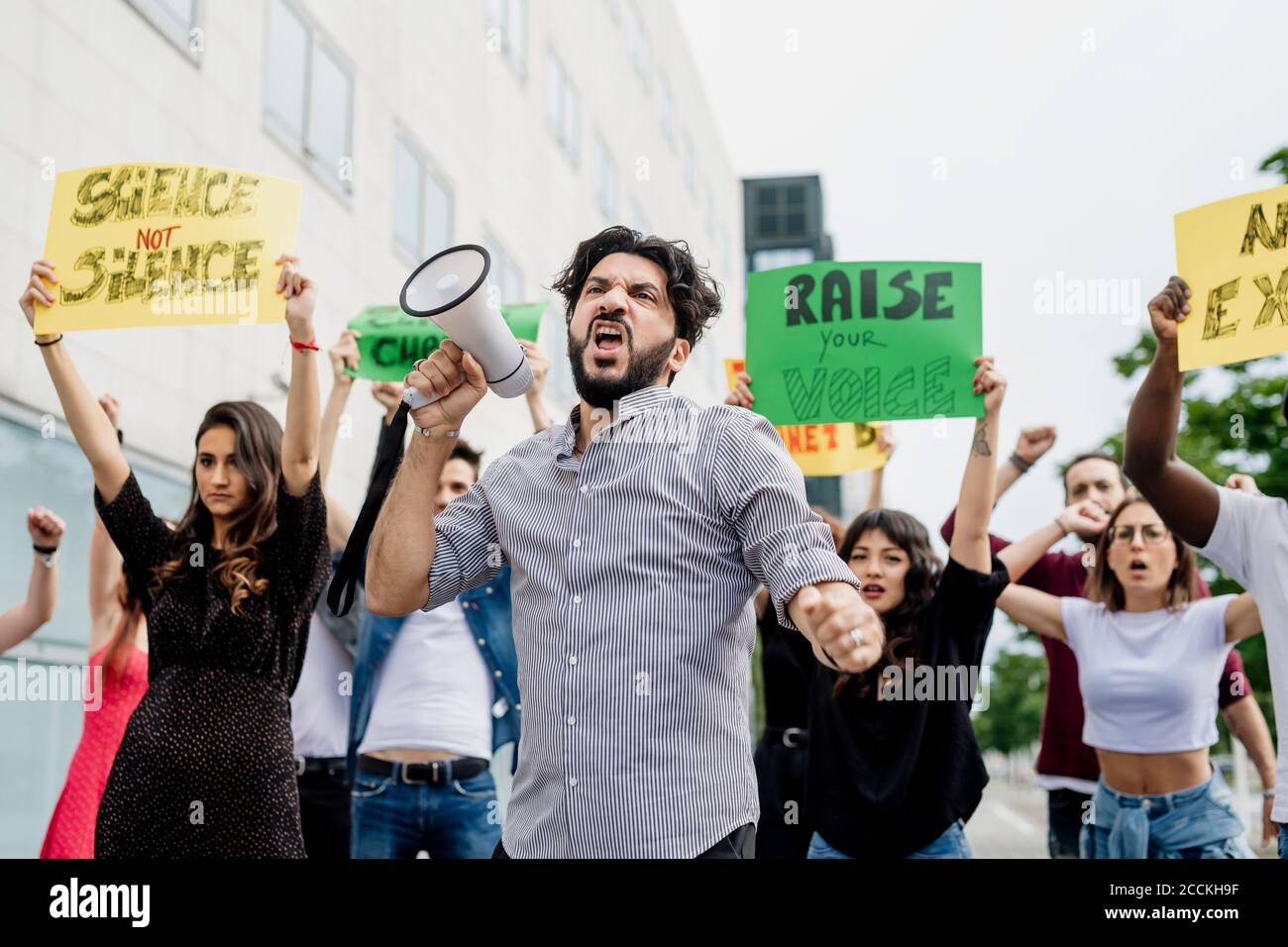 Mann schreit durch Megaphon, während er mit Menschen auf der Straße protestiert In der Stadt Stockfoto